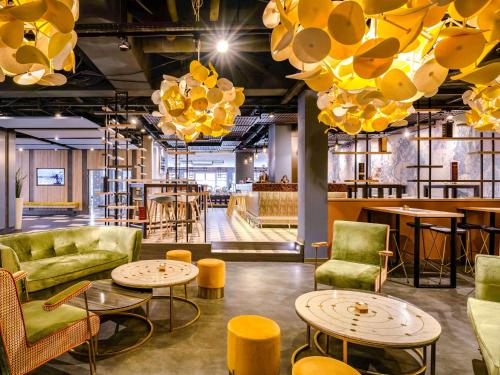 a room with couches tables and chairs and chandeliers at Ibis Styles Regensburg in Regensburg