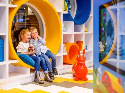 two children sitting in a play room with a mirror at Ibis Styles Regensburg in Regensburg