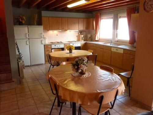 una cucina con due tavoli in legno e una cucina con elettrodomestici bianchi di Cozy Cottage in Baugnez Malmedy with Sauna a Malmedy