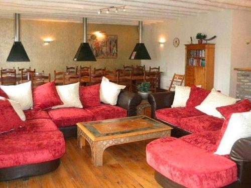 a living room with red couches and a coffee table at Quaint Farmhouse in Maffe with a Turkish Bath in Havelange