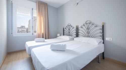 - 2 lits blancs dans une chambre avec fenêtre dans l'établissement R68 Apartamento Montserrat 32-3, à Calafell