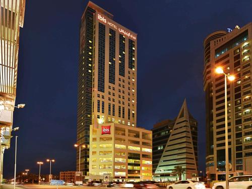 een hoog gebouw in een stad 's nachts bij ibis Seef Manama in Manamah