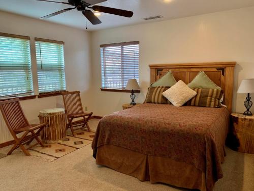 1 dormitorio con 1 cama con 2 sillas y ventilador de techo en Slot Canyons Inn Bed & Breakfast, en Escalante