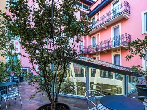 a pink building with tables and chairs and a tree at Ibis Styles Milano Centro in Milan