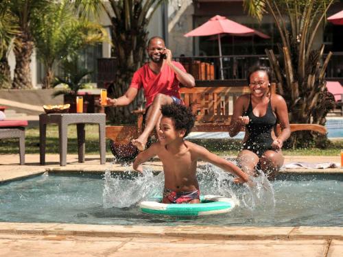 a group of people playing in a swimming pool at Pullman Lubumbashi Grand Karavia. in Lubumbashi