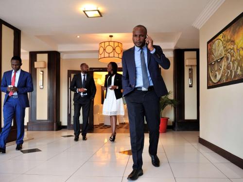 a man walking down a hallway while talking on a cell phone at Pullman Lubumbashi Grand Karavia. in Lubumbashi
