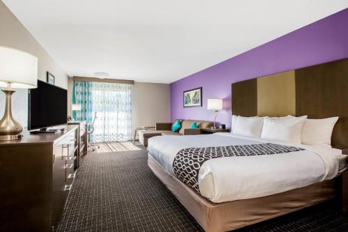 a hotel room with a large bed and a purple wall at La Quinta by Wyndham Pomona in Pomona