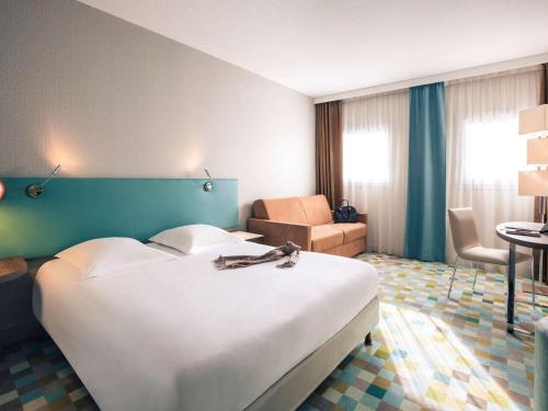 ブシー・サン ・ジョルジュにあるオテル　メルキュール　マルヌ　ラ　ヴァレ　ビュセ　サン　ジョルジュの大きなベッドと椅子が備わるホテルルームです。