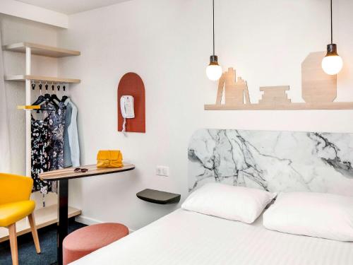 a bedroom with a bed and a desk and a table at Hôtel ibis Styles Vichy Centre in Vichy