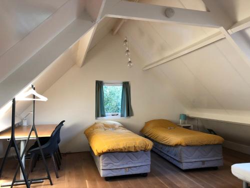 2 bedden in een zolderkamer met een bureau en een raam bij Green Garden House in Amersfoort