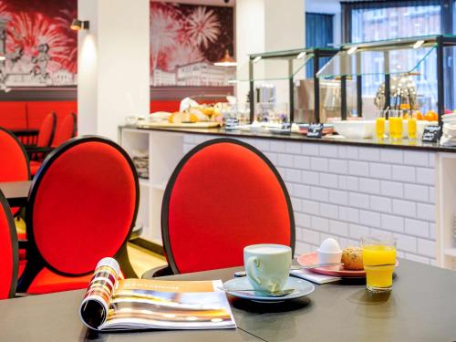 a table with red chairs and a tableasteryasteryasteryasteryasteryasteryasteryastery at ibis Styles Halle in Halle an der Saale