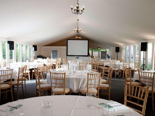 a conference room with tables and chairs and a screen at Hunton Park Hotel in Kings Langley
