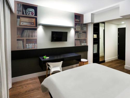 ein Schlafzimmer mit einem Bett, einem Schreibtisch und einem Fernseher in der Unterkunft ibis Styles Taubate in Taubaté