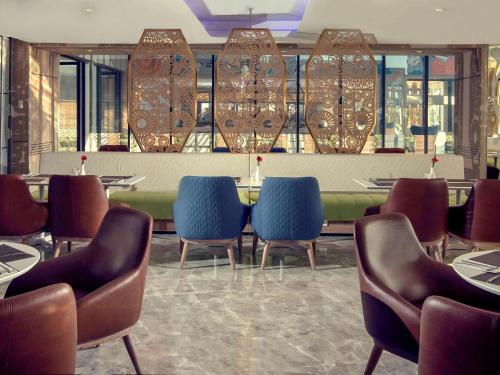 a restaurant with chairs and a table and a bar at Mercure Bandung City Centre in Bandung