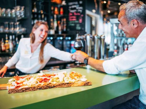 a man handing a woman a glass of wine at a bar at Novotel Paris Coeur d'Orly Airport in Orly