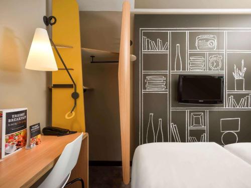 um quarto com uma cama e uma televisão na parede em Ibis Brussels Erasmus em Bruxelas