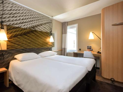 a hotel room with a large white bed with two pillows at Ibis Brussels Erasmus in Brussels