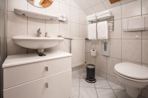 une salle de bain blanche avec un lavabo et des toilettes dans l'établissement Kolmsteiner Hof, à Neukirchen beim Heiligen Blut