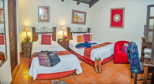 a bedroom with two beds and a red chair at Hotel Meson del Valle by AHS in Antigua Guatemala