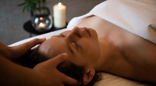 a man laying on a bed with a towel on his head at Río Serrano Hotel + Spa in Torres del Paine