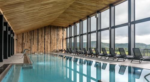 a pool with chairs in a building with windows at Río Serrano Hotel + Spa in Torres del Paine