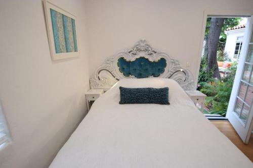a white bed with a blue pillow on top of it at Beverly Hills Celebrity Home in Los Angeles