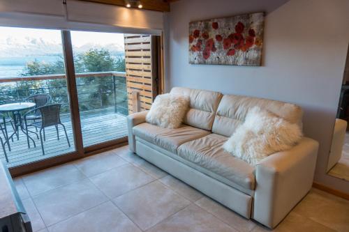 un sofá de cuero en una sala de estar con balcón en BOG Atardeceres del lago - piscina climatizada y vistas al lago en Villa La Angostura