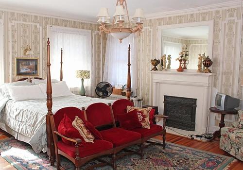 a bedroom with a bed with a red chair and a fireplace at Port City Guest House in Wilmington