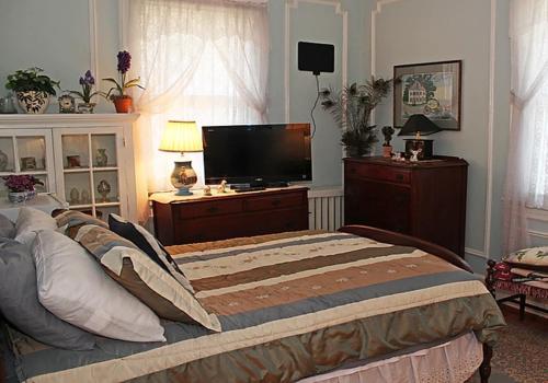 una camera con un grande letto e una TV a schermo piatto di Port City Guest House a Wilmington