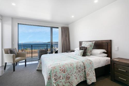 a bedroom with a bed and a view of the ocean at Acacia Lake View Motel in Taupo