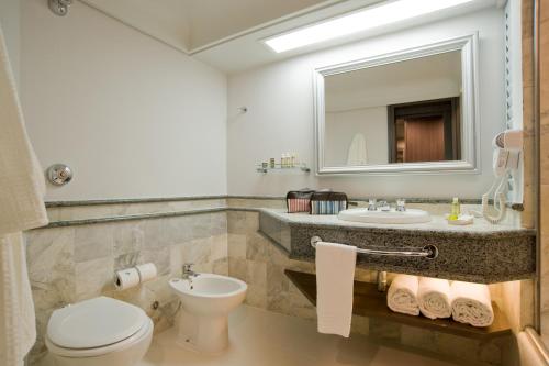 a bathroom with a toilet, sink and mirror at Slaviero Curitiba Centro in Curitiba