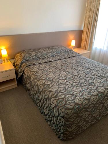 a bedroom with a bed and two night stands with lamps at Shellharbour Resort and Conference Centre in Shellharbour