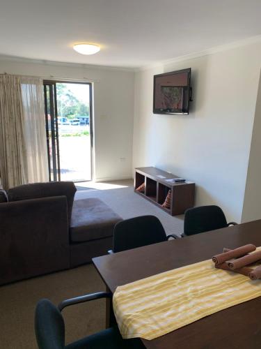 a living room with a couch and a tv on the wall at Shellharbour Resort and Conference Centre in Shellharbour