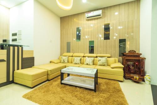 a living room with a yellow couch and a table at Paradise Hotel in Củ Chi