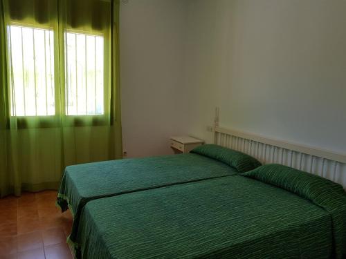 a bedroom with a green bed and two windows at PORT LA SARDANA EmpuriaRent in Empuriabrava