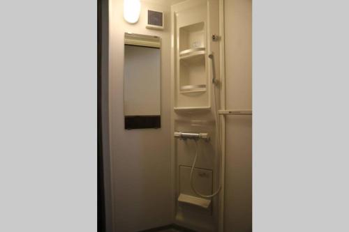 a small bathroom with a door and a refrigerator at Yoshiki no Sato Dainichi no Yado in Hida