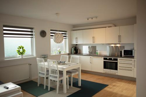 a kitchen with white cabinets and a table and chairs at Mørk Apartments- Great View in Tórshavn