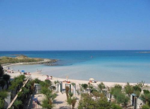 una spiaggia con persone sulla sabbia e sull'acqua di Appartamento Potì sulla spiaggia a Porto Cesareo