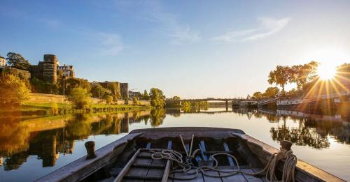 a boat on a river with the sun setting at Logis de l'Hermitage in Le Louroux-Béconnais