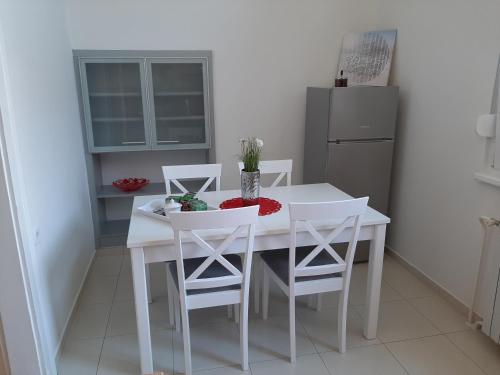 a white dining room table with white chairs and a refrigerator at Apartman Kod Kestena in Osijek