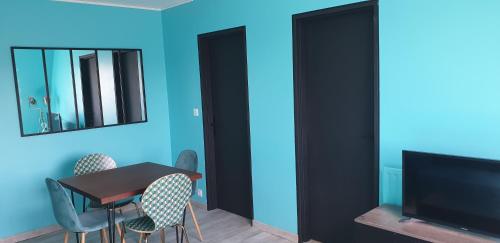 a dining room with a table and chairs and a television at Home sweet home Cabourg plage in Cabourg