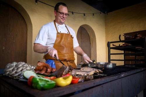 a man in a kitchen preparing food on a grill at Sigtunastiftelsen Hotell & Konferens in Sigtuna