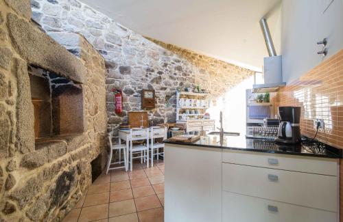 une cuisine avec un mur en pierre et un comptoir dans l'établissement Pazo Da Cruz, à Villarmayor