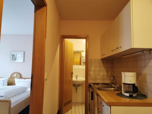 a small kitchen with a sink and a bed in a room at Hotel Ebner in Bad Königshofen im Grabfeld