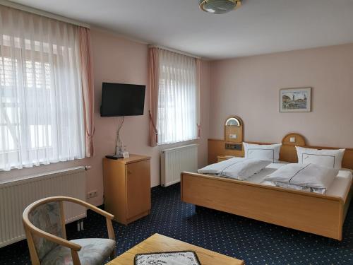 a bedroom with a bed and a tv and a chair at Hotel Ebner in Bad Königshofen im Grabfeld