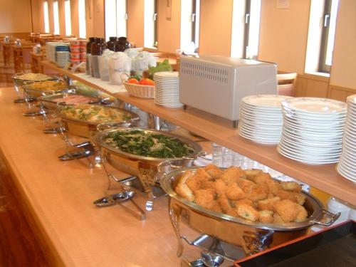 a buffet line with plates and bowls of food at Hotel Route-Inn Nagaoka Ekimae in Nagaoka