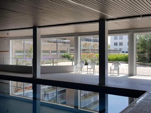 a group of chairs sitting on the balcony of a building at Appartement in residentie Silverbeach met binnenzwembad in De Haan