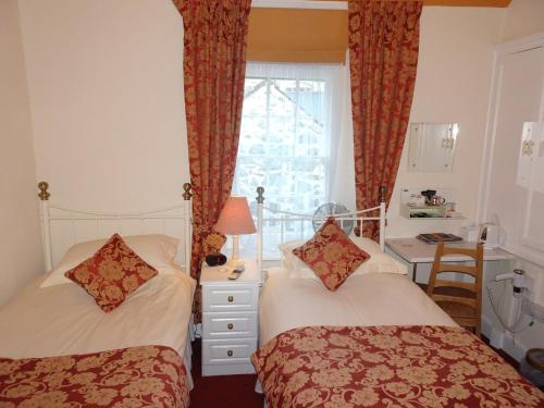 a hotel room with two beds and two windows at Ivy House B&B in Dolgellau