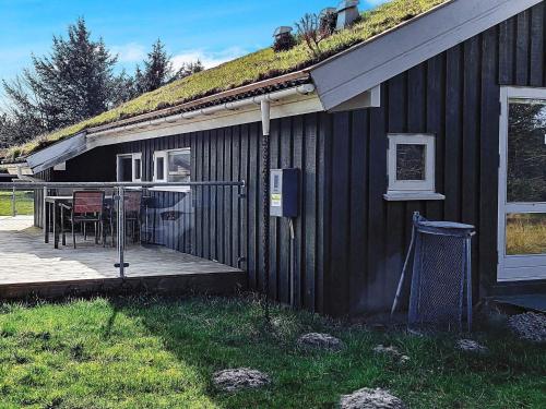 una casa negra con una terraza con una mesa. en 6 person holiday home in Pandrup en Rødhus
