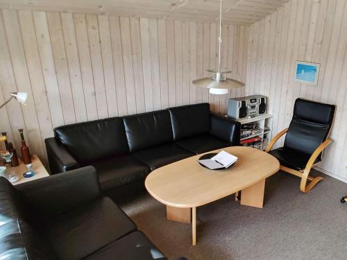 Rødhusにある6 person holiday home in Pandrupのリビングルーム(黒いソファ、テーブル付)